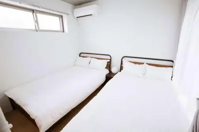 two beds in a room with a window at Laffitte Hirai Condominium Hotel in Tokyo