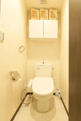a bathroom with a toilet with a phone next to it at Ruma Inn Ikebukuro in Tokyo