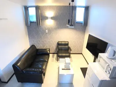 a living room with a leather couch and a television at Ruma Inn Ikebukuro in Tokyo