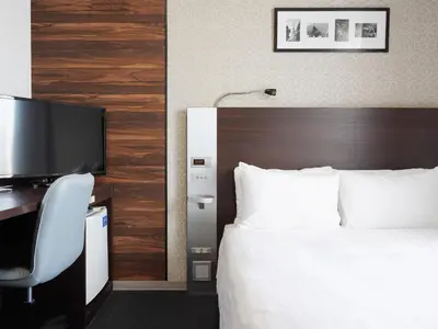 a bedroom with a bed and a desk with a television at Comfort Hotel Tokyo Higashi Nihombashi in Tokyo
