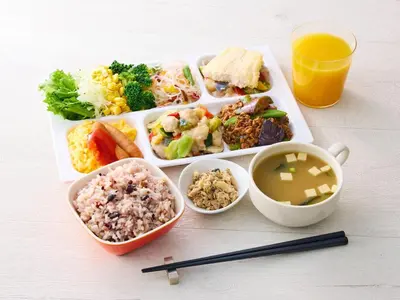 a plate of food with different foods and a glass of orange juice at Comfort Hotel Tokyo Kanda in Tokyo