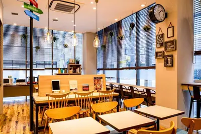 a restaurant with tables and chairs and a clock on the wall at Comfort Hotel Tokyo Kanda in Tokyo