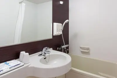 a bathroom with a sink and a mirror and a tub at Comfort Hotel Tokyo Kanda in Tokyo