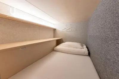 a small room with a bed and a wall at unito CHIYODA in Tokyo