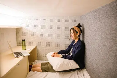 a woman sitting on a bed in a room at unito CHIYODA in Tokyo
