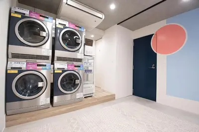 two washing machines in a laundry room with a blue door at unito CHIYODA in Tokyo