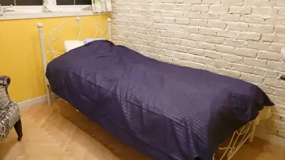 a bed with a purple comforter next to a brick wall at \u30db\u30c6\u30eb The Standard Apartment Shibuya D 2020\u5e74\u30aa\u30fc\u30d7\u30f3 in Tokyo