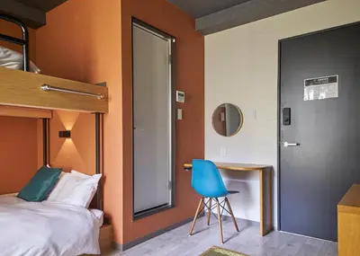a bedroom with a bed and a blue chair at IKIDANE Residential Hotel Sumida Kyojima in Tokyo