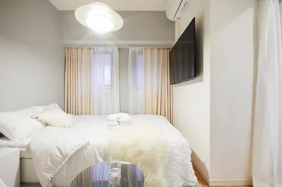 a bedroom with a bed with white sheets and a tv at P OIN T - Shinjuku Kabukicho Designer's Apartment I in Tokyo