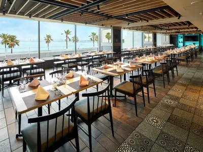 a restaurant with tables and chairs with the ocean in the background at Grand Nikko Tokyo Bay Maihama in Urayasu