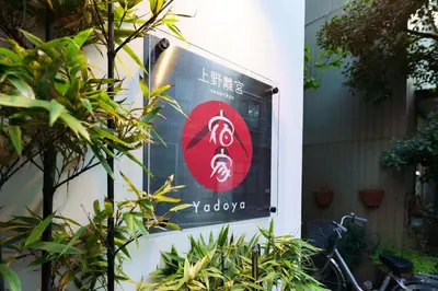 a sign on the side of a building with plants at YADOYA Ueno-Rikyu in Tokyo