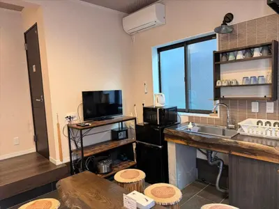 a room with a kitchen with a sink and a tv at YADOYA Ueno-Rikyu in Tokyo