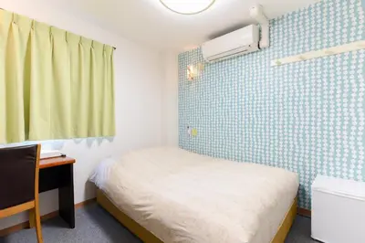 a small room with a bed and a sink at Otsuka Town Hotel in Tokyo