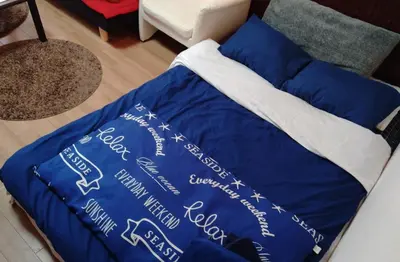 a bed with a blue blanket on top of it at Lions Mansion Dogenzaka 207 in Tokyo