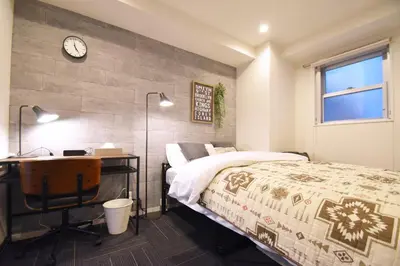 a bedroom with a bed and a desk and a clock at Tune Inn Tokyo Bay in Tokyo