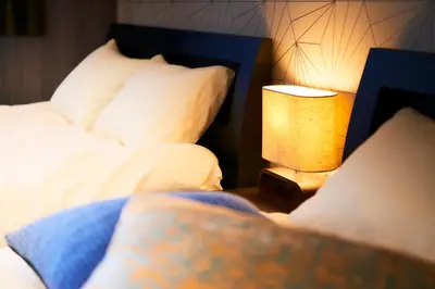 a bedroom with a bed and a lamp on a table at S'CASA NishiShinjuku in Tokyo