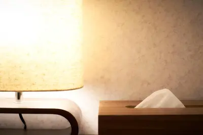 a lamp sitting on a table next to a bed at S'CASA NishiShinjuku in Tokyo