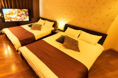 a hotel room with two beds and a tv at S'CASA NishiShinjuku in Tokyo