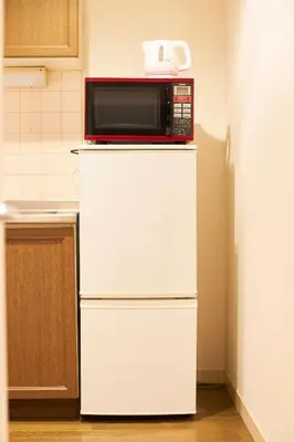 a microwave on top of a white refrigerator in a kitchen at S'CASA NishiShinjuku in Tokyo
