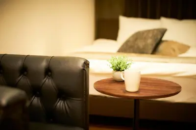 a table with two cups on it next to a bed at S'CASA NishiShinjuku in Tokyo