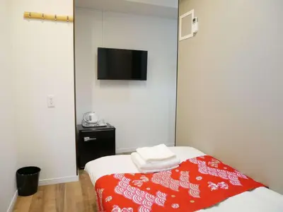 a room with a bed with a red blanket and a flat screen tv at Tokyo shinjukutei Hotel Asahi gruop \u6771\u4eac\u65b0\u5bbf\u4ead\u30db\u30c6\u30eb in Tokyo