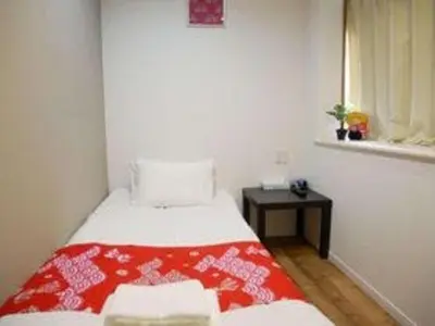 a bedroom with a bed with a red and white blanket at Tokyo shinjukutei Hotel Asahi gruop \u6771\u4eac\u65b0\u5bbf\u4ead\u30db\u30c6\u30eb in Tokyo