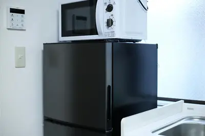 a microwave sitting on top of a black refrigerator at MUMU HOUSE in Tokyo