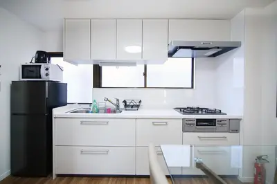 a kitchen with white cabinets and a black refrigerator at MUMU HOUSE in Tokyo