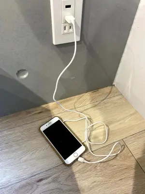 a cell phone plugged into an outlet on the floor at Belle harmonie togoshi101 in Tokyo