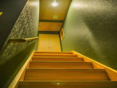 a staircase in a room with green walls and wooden stairs at YADOYA Karasumain in Tokyo