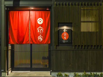 a gate with a red curtain in front of a building at YADOYA Karasumain in Tokyo