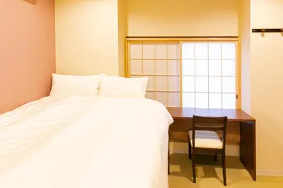 a bedroom with a bed and a desk and a chair at Wa no Kaede in Tokyo
