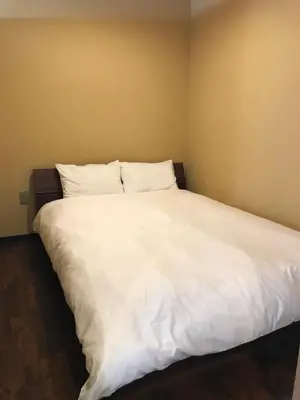 a bed with white sheets and pillows in a room at Wa no Kaede in Tokyo