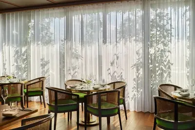 a dining room with a table and chairs and curtains at The Tokyo EDITION, Toranomon in Tokyo