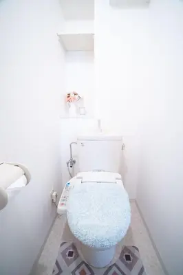 a bathroom with a white toilet with a blue seat at Elle's Shirokane Guest house in Tokyo