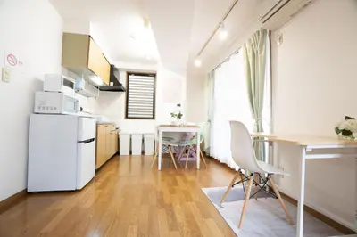 a kitchen with a white refrigerator and a table at Elle's Shirokane Guest house in Tokyo