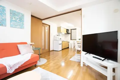 a living room with a couch and a flat screen tv at Elle's Shirokane Guest house in Tokyo