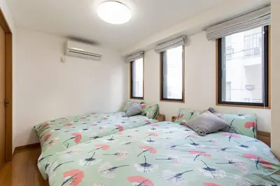 a bedroom with a bed and two windows at Elle's Shirokane Guest house in Tokyo
