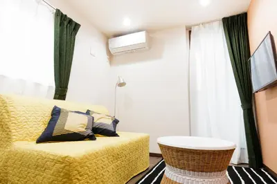 a living room with a yellow bed and a window at Crescent Moon Nakanoshimbashi in Tokyo