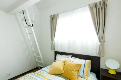 a bedroom with a bed with yellow pillows and a window at Crescent Moon Nakanoshimbashi in Tokyo