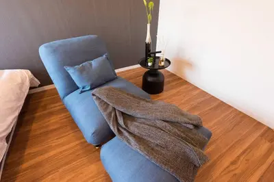a living room with a blue chair and a blanket at TORA HOTEL Tokyo Skytree \u5bc5\u30db\u30c6\u30eb \u30b9\u30ab\u30a4\u30c4\u30ea\u30fcC in Tokyo