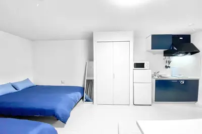 a bedroom with a blue bed and a small kitchen at FL Residence Takadanobaba in Tokyo