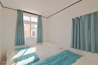 a bedroom with a bed with blue curtains and a window at V.Close to Nishi-Shinjuku/FrWIF/ Roof top Terrace in Tokyo