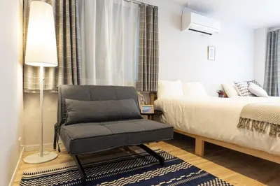 a bedroom with a bed and a chair and a lamp at SAKURA INN Asakusa station walking 4 Min Shinjuku Shibuya Ginza Oshiage in Tokyo