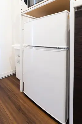 a white refrigerator in a kitchen next to a wall at GIVE Higashi Nakano in Tokyo
