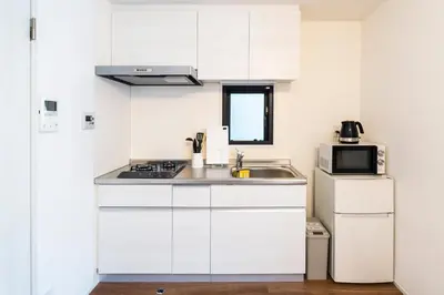 a white kitchen with a sink and a microwave at GIVE Araiyakushi in Tokyo