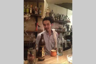 a man sitting at a bar with a bottle of alcohol at Dwell Urban 6C in Tokyo