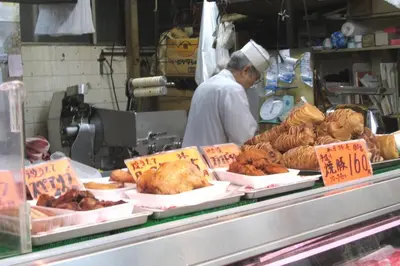 a man in a kitchen preparing chickens and other food at Dwell Urban 6C in Tokyo