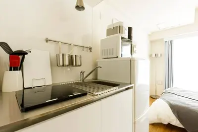 a kitchen with a counter with a stove and a refrigerator at Dwell Urban 4C in Tokyo