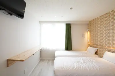 two beds in a room with a window at U-Hotel Takadanobaba in Tokyo